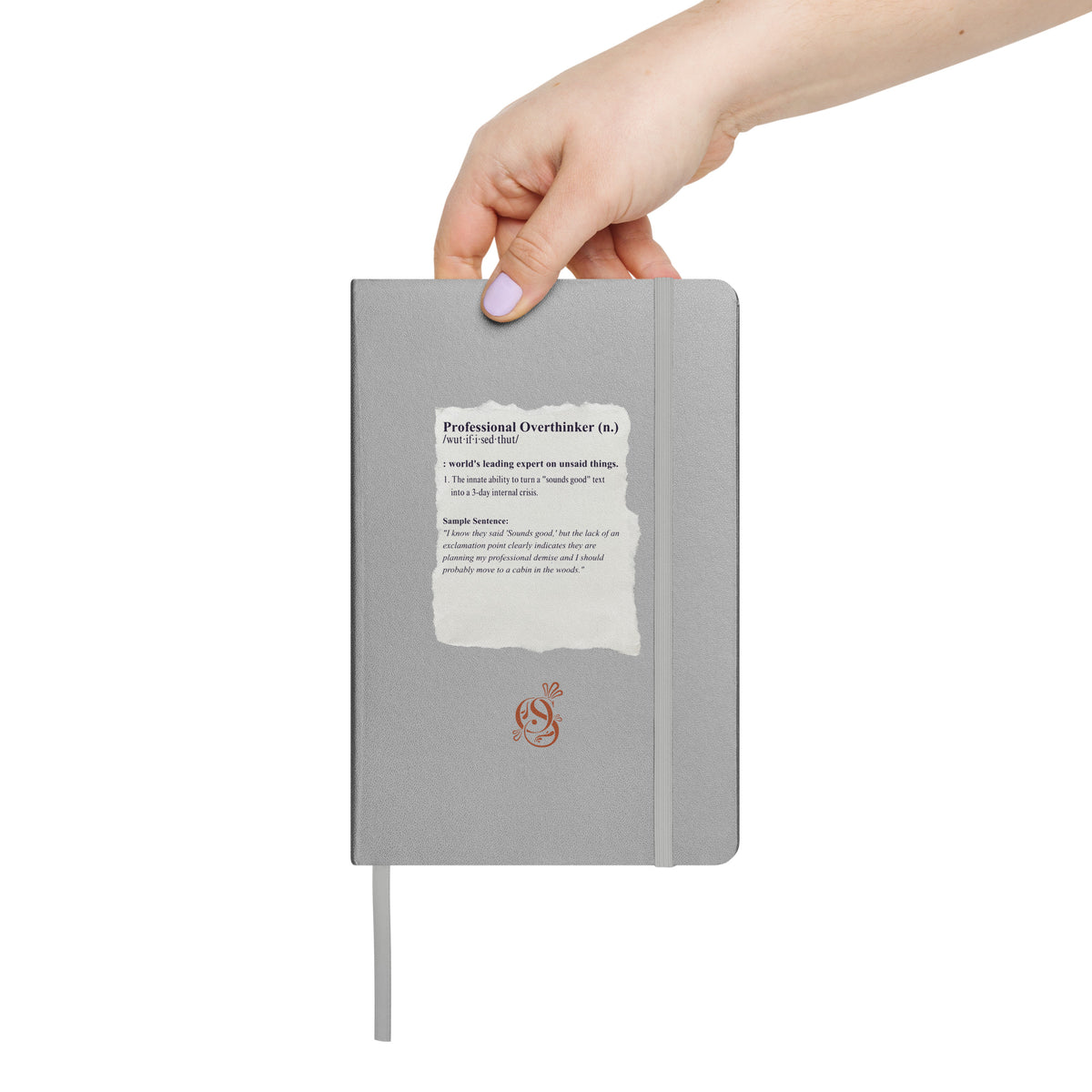 A hand holding the matte silver-gray hardcover notebook.
